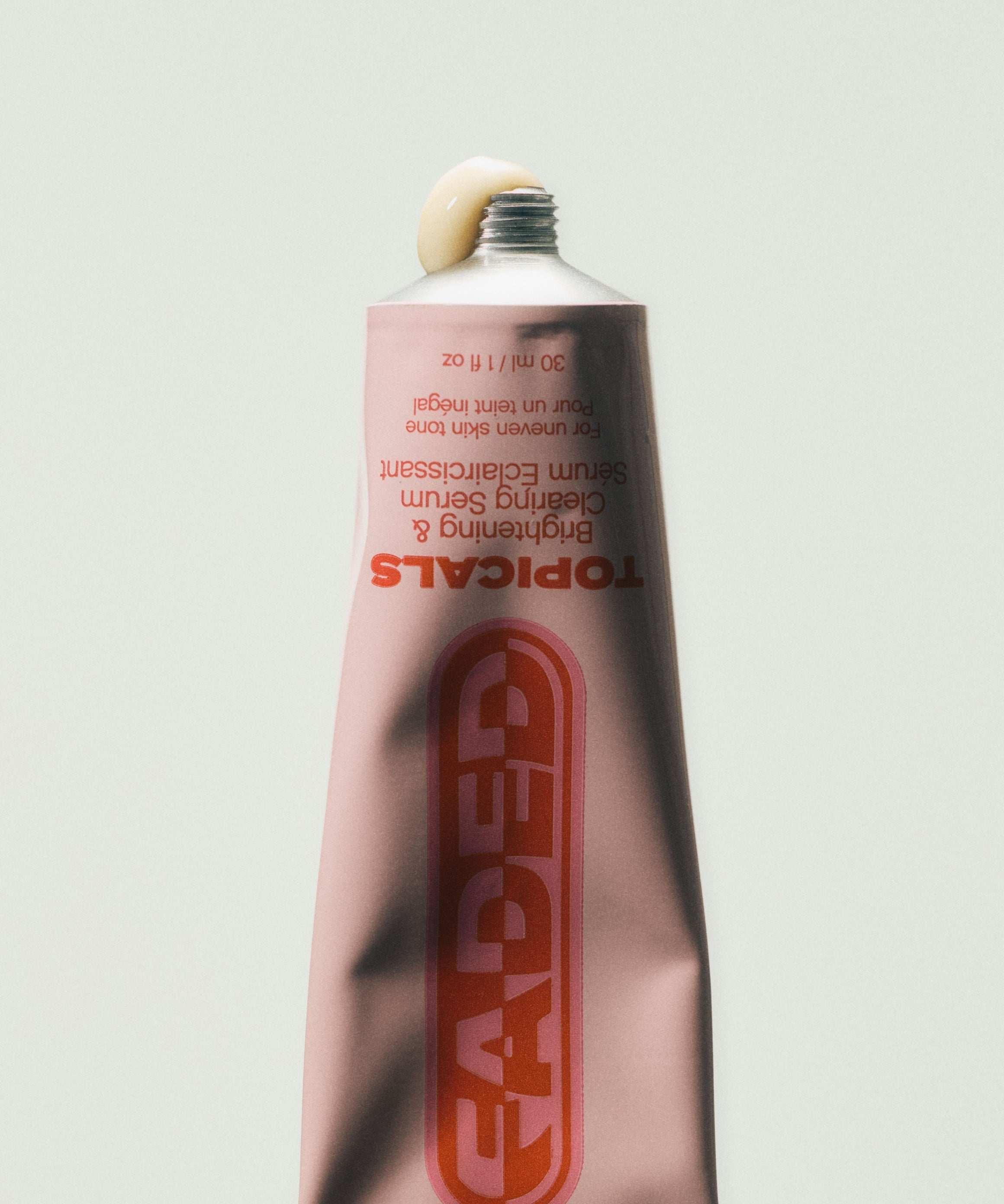 Dark spot serum tube from Topicals Faded photographed upside down with a drop of cream formula visible at the open cap.