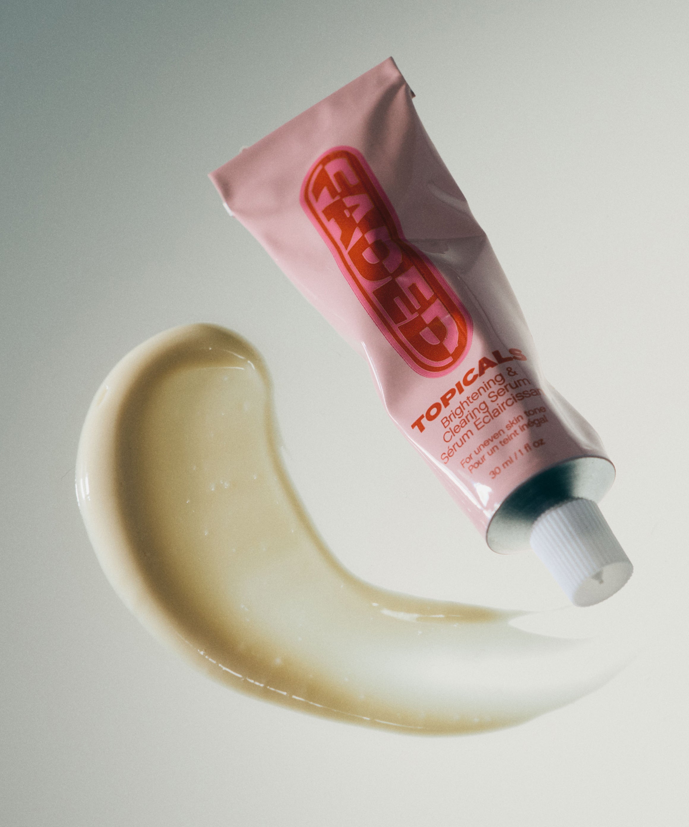 Serum for hyperpigmentation from Topicals Faded floating above a curved swipe of cream-colored texture on a light background.