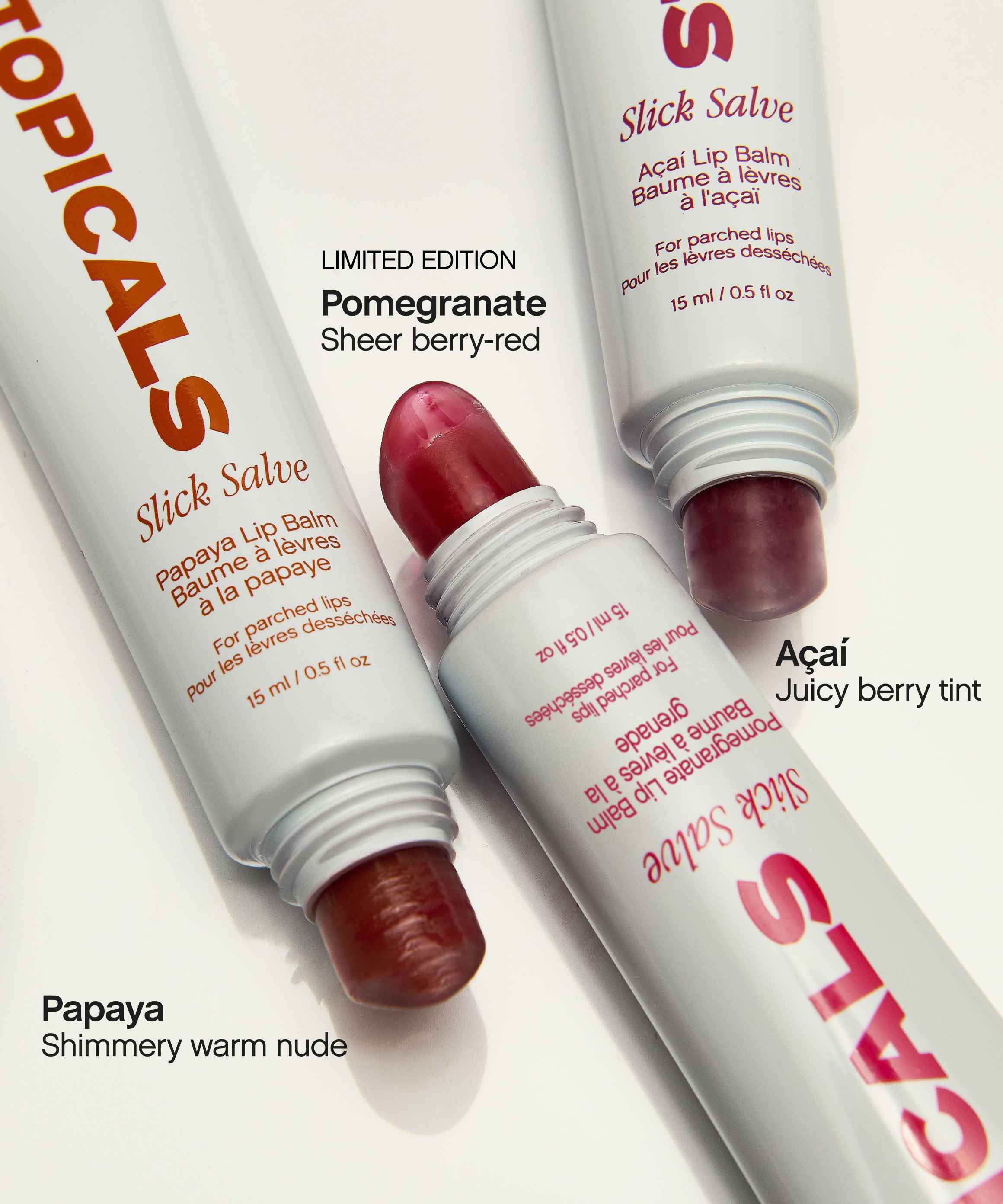 Three uncapped Topicals Slick Salve lip balms in Pomegranate, Papaya, and Açaí, displayed as part of the moisturizing lip balm trio.