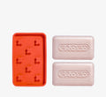 Brightening cleansing bar set from Topicals Faded showing two pink embossed bars alongside a red silicone soap dish with flower-shaped ridges on a white background.
