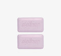 Exfoliating cleansing bars from Topicals Slather shown as a pair of speckled lavender bars with embossed branding on a white background.