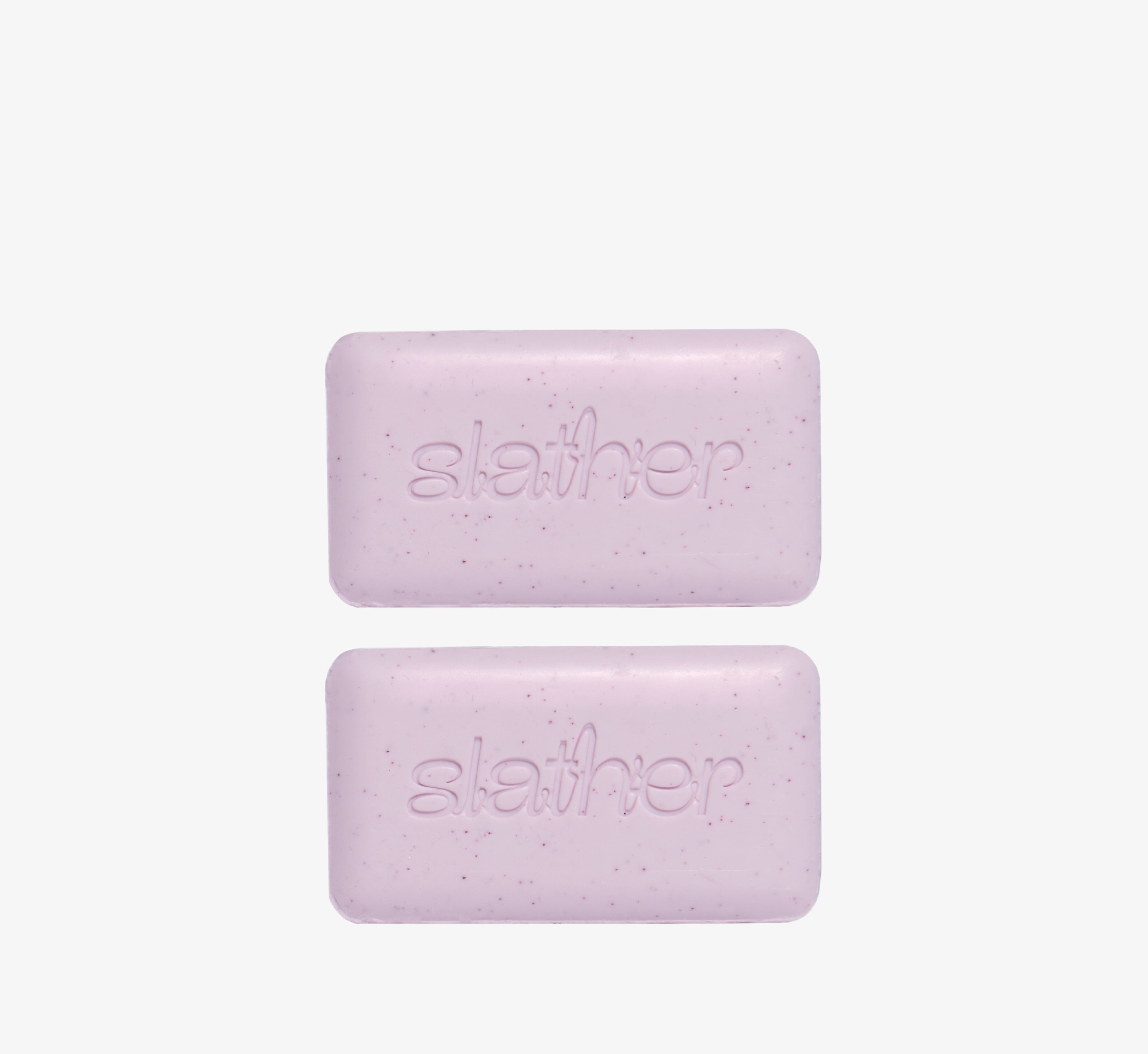 Exfoliating cleansing bars from Topicals Slather shown as a pair of speckled lavender bars with embossed branding on a white background.