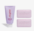 Exfoliating body care bundle from Topicals Slather featuring a lavender 150ml Exfoliating Body Serum tube alongside two pink Slather exfoliating cleansing bars on a white background.