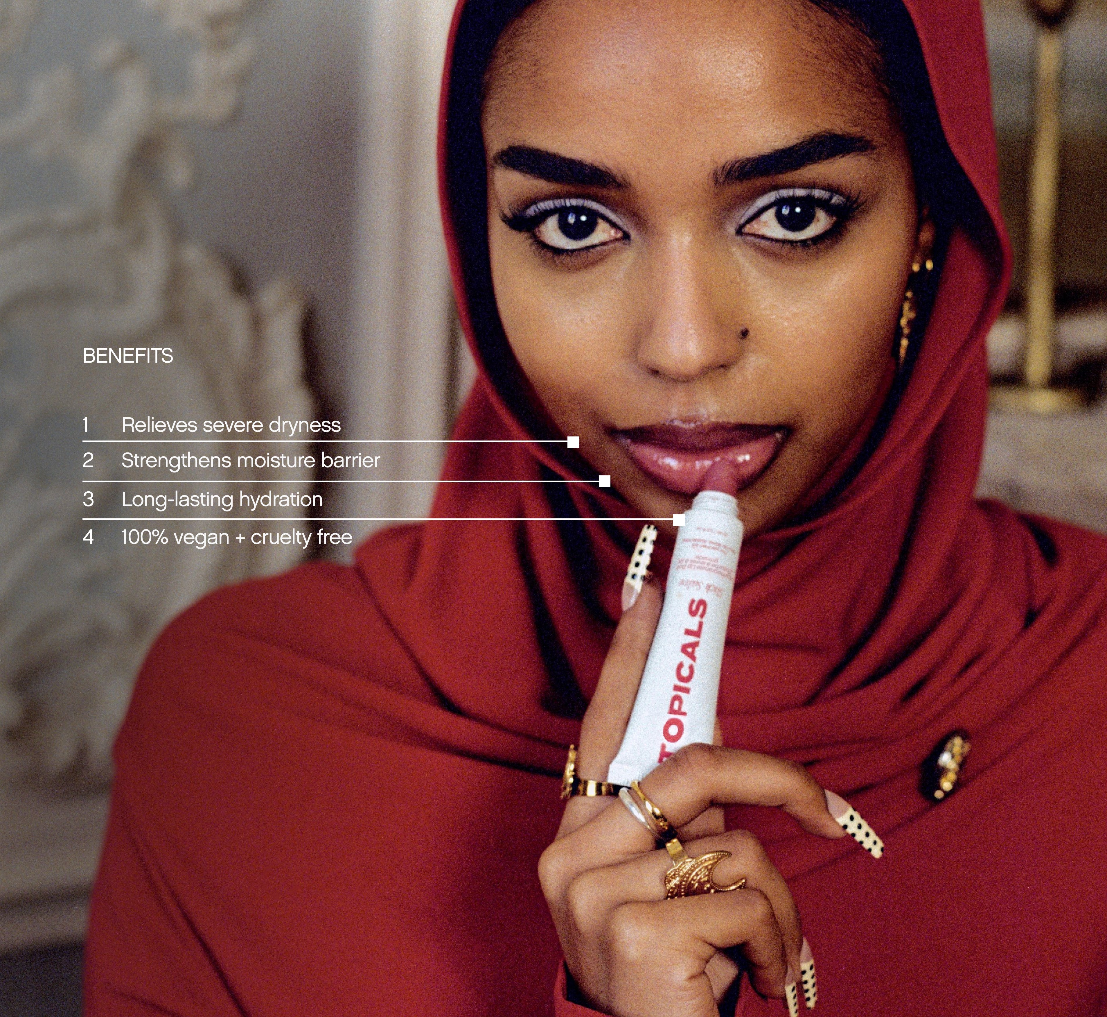Moisturizing lip balm from Topicals Slick Salve held up to glossy lips by a woman in a red hijab, with benefits callouts for dryness relief, moisture barrier strengthening, and vegan formula.