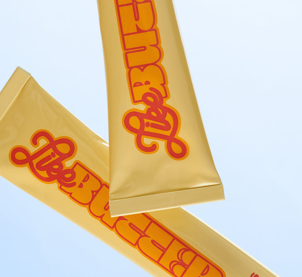 Two squeezed Topicals Like Butter moisturizer tubes crossed against a pale blue background, showing the well-loved hydrating cream packaging.