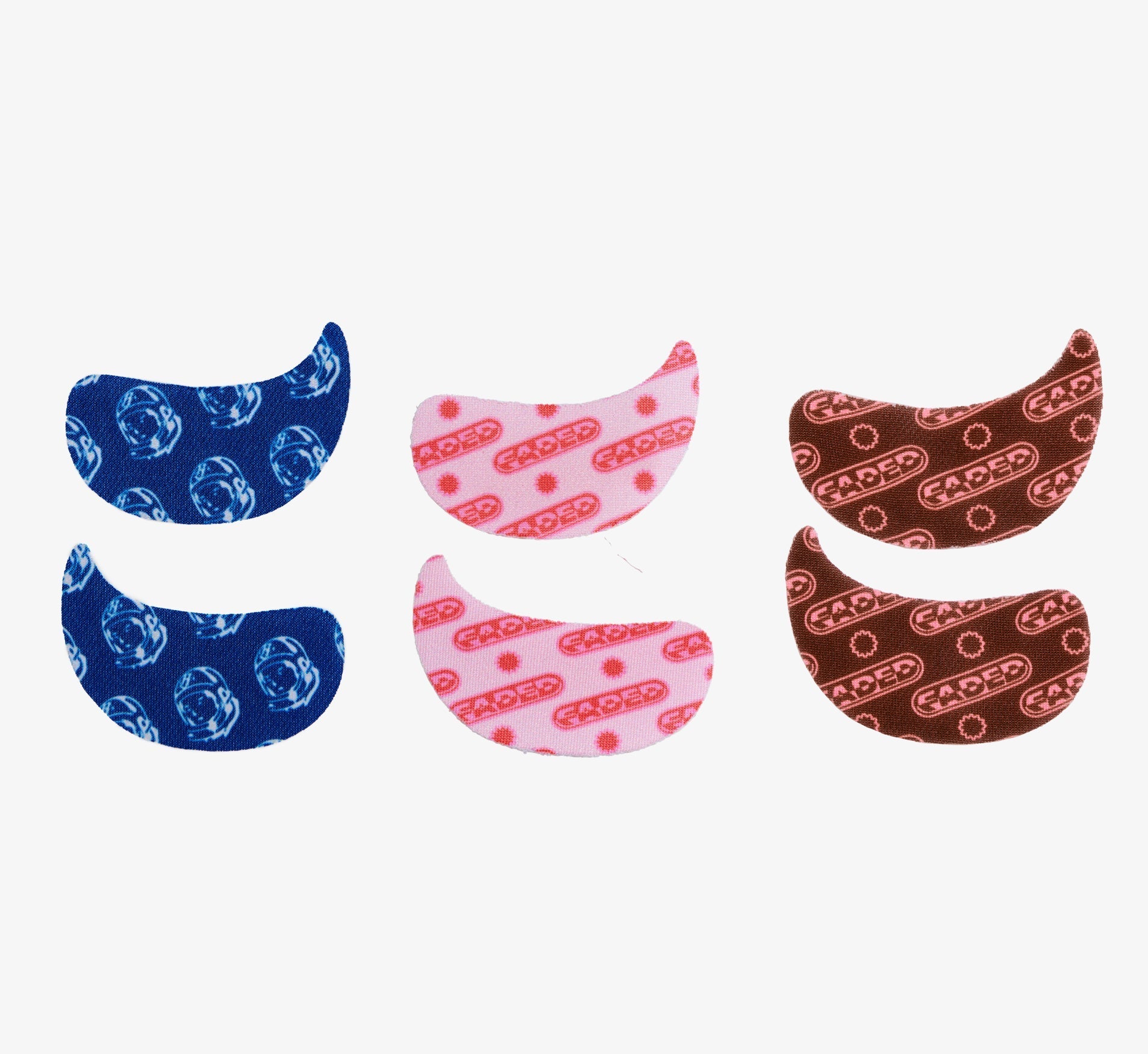 Brightening under eye patches from Topicals Faded shown in three colorways — blue astronaut print, pink, and brown — displayed as pairs on a white background.