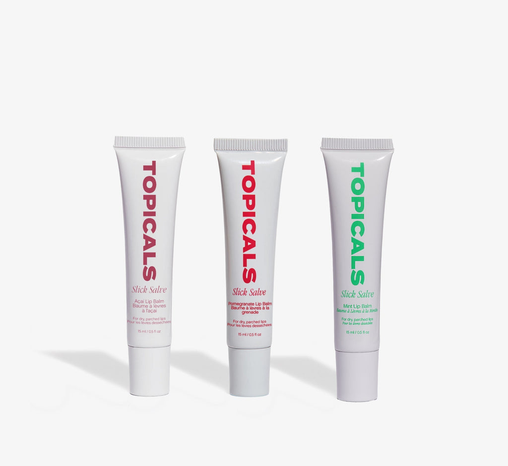 Moisturizing lip balm trio from Topicals Slick Salve in Açaí, Pomegranate, and Mint standing upright side by side on a white background.